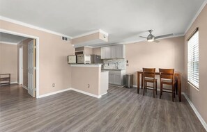 A spacious kitchen with a dining area, wooden flooring, and a ceiling fan.