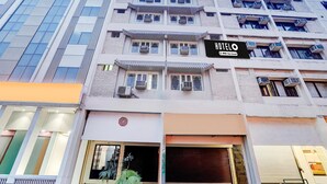 A multi-story hotel with balconies, air conditioning units, and a sign indicating it is a hotel.