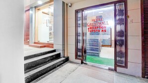 A hotel reception area with a glass door, a set of stairs leading to the entrance, and a visible outdoor area.