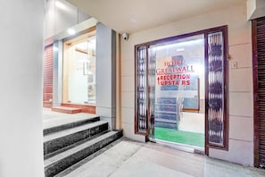 A hotel reception area with a glass door, a set of stairs leading to the entrance, and a visible outdoor area. - Super Deluxe Room Hotel O Clock Tower (Ludhiana)