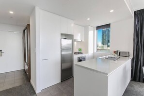 A modern kitchen with a central island, stainless steel appliances, and a window with a city view. - lovely 2 bds in heart chatswood free parking (Chatswood)