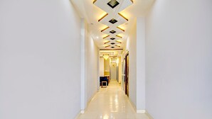 A long, narrow hallway with a glossy tiled floor and a ceiling with geometric patterns and recessed lighting. - Premium Anisabad Near Mahavir Sansthan (Patna)