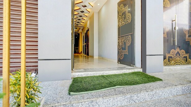 A modern building entrance with a glass door, a patterned wall, and a small green area. - Premium Anisabad Near Mahavir Sansthan (Patna)
