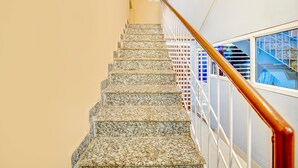 A staircase with a wooden handrail, leading to a landing with a glass railing. - Premium Anisabad Near Mahavir Sansthan (Patna)