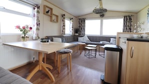 Un espace de vie compact comprenant un coin cuisine, un coin repas et un espace détente avec un canapé et une table.