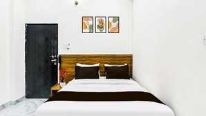 A hotel room with a bed, a wooden headboard, a black door, and three framed pictures on the wall. - Classic With Balconybhu IIT Mahamanpuri BLW (Varanasi)