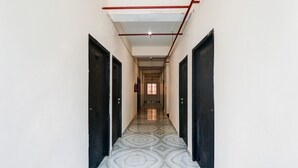 A hallway with patterned flooring, black doors, and a ceiling with exposed pipes. - Classic With Balconybhu IIT Mahamanpuri BLW (Varanasi)