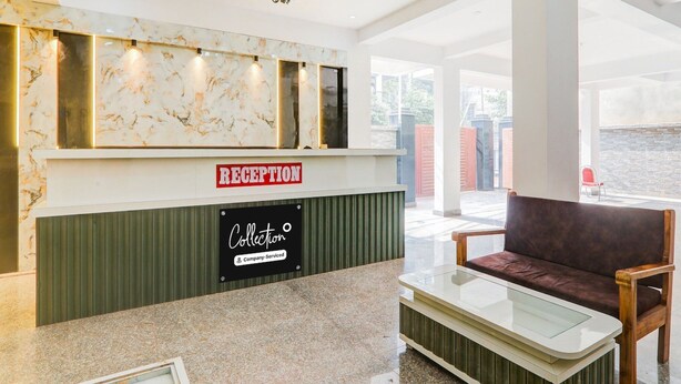 A reception area with a marble wall, a reception desk, a sign reading 'RECEPTION,' a sign for 'Collection,' and a brown leather sofa. - Classic With Balconybhu IIT Mahamanpuri BLW (Varanasi)
