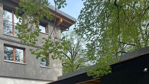 Una casa moderna de dos pisos con garaje cubierto, un pequeño jardín y un buzón a la vista.