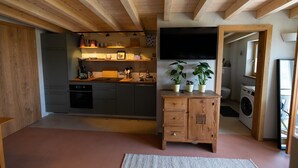 Cocina moderna con vigas de madera, horno empotrado y un mueble de madera con plantas.