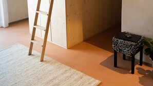 Una cama litera con una escalera, una mesita con un ratón y un cuadro en la pared.