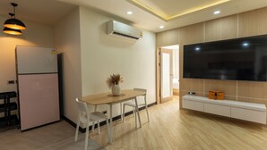 Una cocina moderna con refrigerador, mesa de comedor, sillas y un televisor de pantalla plana montado en la pared.