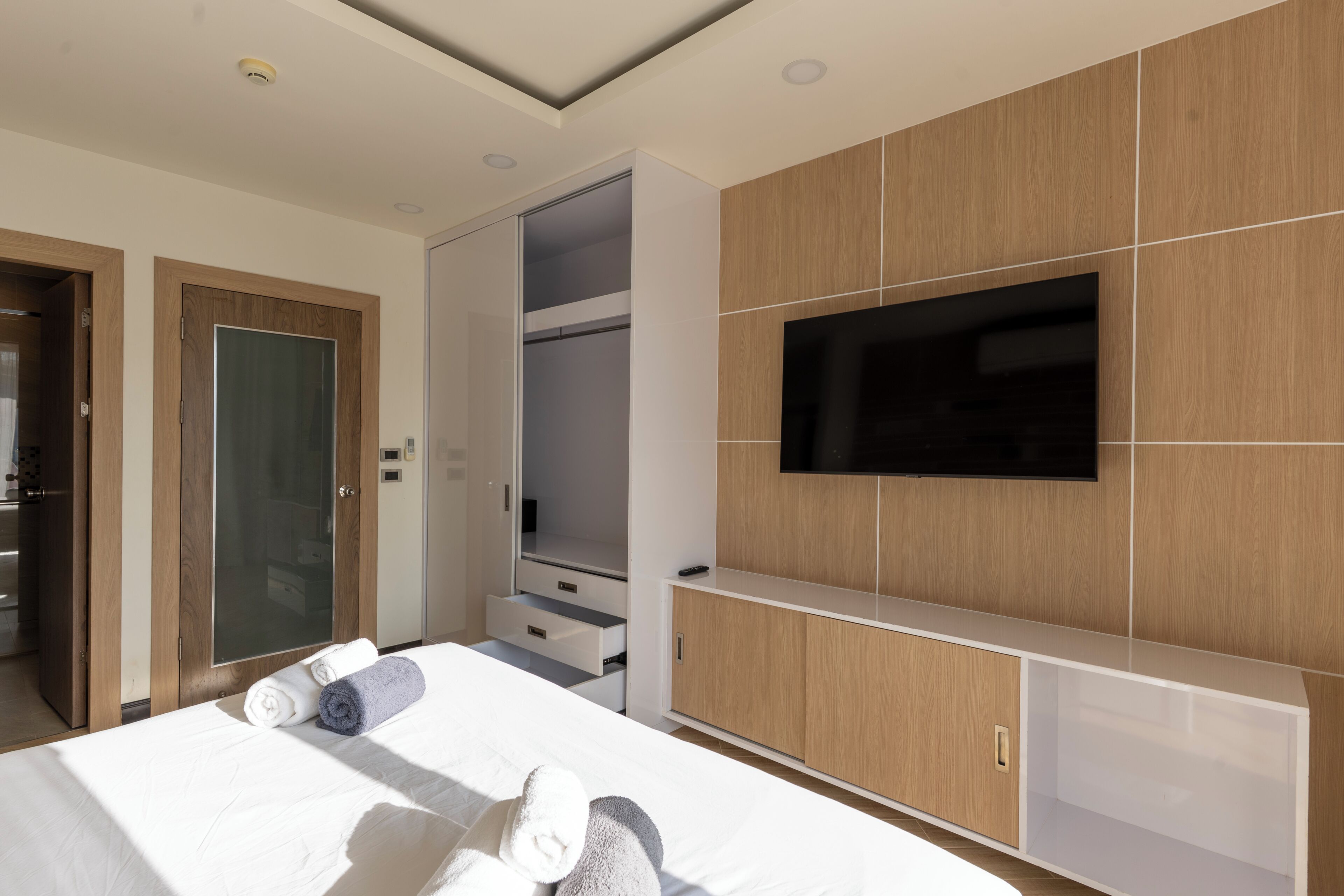 Ett hotellrum med en säng, en tv som är monterad på väggen, en garderob och ett badrum som syns genom en öppen dörr.