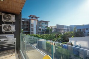 Ein Balkon mit Samsung-Klimaanlagen, einer Glastrennwand und Blick auf umliegende Gebäude.