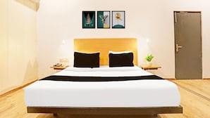 Una cama con cabecera de madera, una mesita de noche con un teléfono y una planta pequeña.