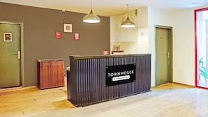 Una mesa de recepción con la etiqueta 'TOWNHOUSE' y un cartel de la empresa, suelo de madera y dos puertas.