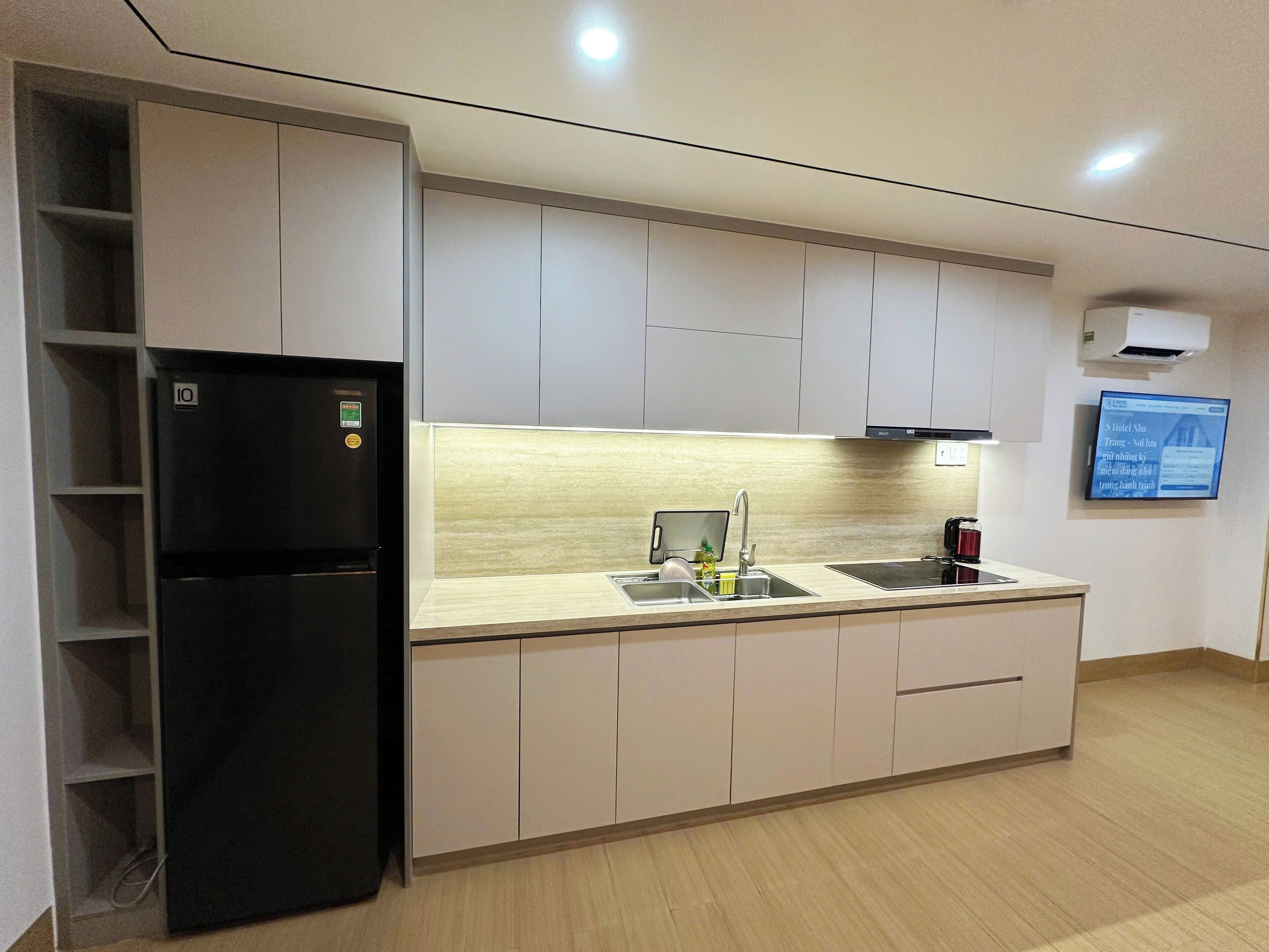 A modern kitchen with a black refrigerator, a sink, and a stove.