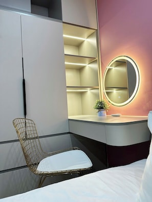 Une chambre à coucher comprenant un lit, une chaise, une coiffeuse avec un miroir et des étagères intégrées.
