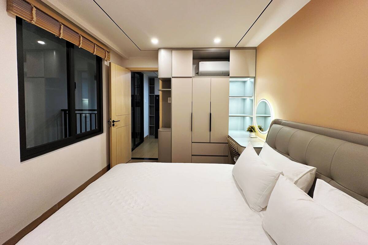 Una habitación de hotel con cama, tocador con espejo y armario.