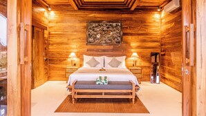 Un dormitorio con paneles de madera, una cama grande, dos mesitas de noche, un espejo y una obra de arte en el techo.