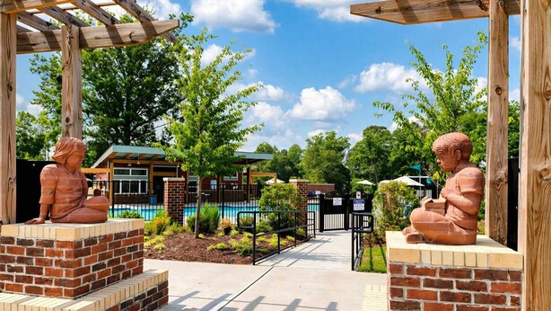 A courtyard with two terracotta statues, a brick pool, and a covered seating area. - Lux 4BR,3.5Bath townhome, perfect for groups (Cary)