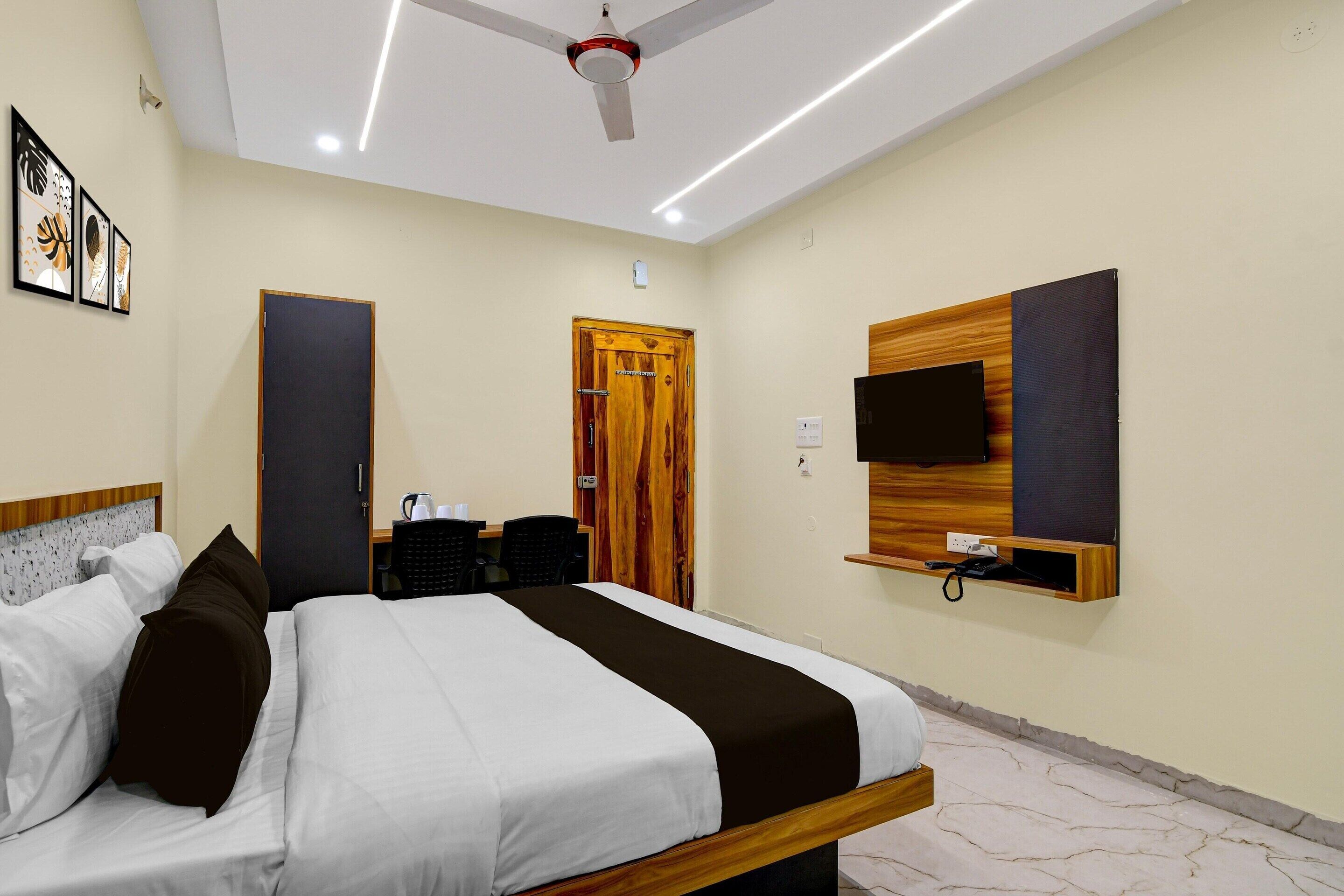 Ein Hotelzimmer mit Bett, Schreibtisch, Stuhl, Wand-Fernseher und Deckenventilator.