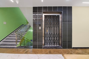 A staircase with a green wall, a black tiled wall, and a metal gate. - Deluxe Siva Karthikeya Residency (Parvathipuram)