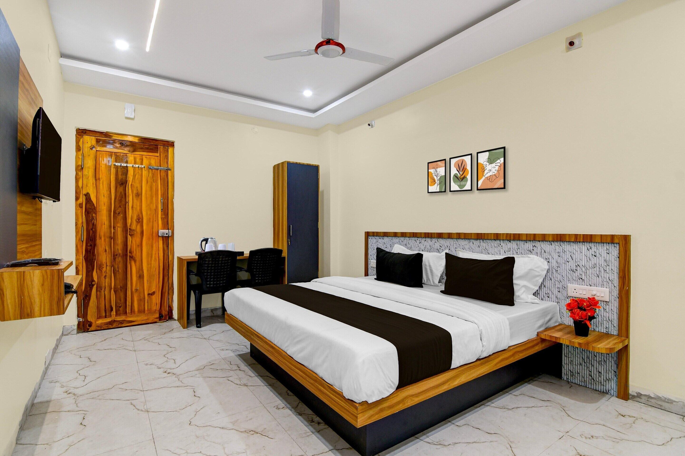 A bedroom with a bed, a desk, a chair, a wardrobe, and a ceiling fan.