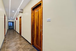 A hallway with wooden doors, a tiled floor, and a ceiling with recessed lighting. - Deluxe Siva Karthikeya Residency (Parvathipuram)