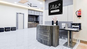 A reception area with a counter, a sign indicating it's a company-serviced collection point, a ceiling fan, and a fire extinguisher. - Premium Collection O Joka Industrial Plaza (Alipur)