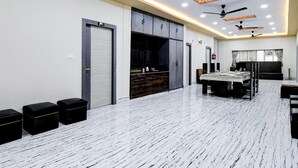 A modern hotel room with a large dining table, built-in cabinets, and ceiling fans. - Premium Collection O Joka Industrial Plaza (Alipur)