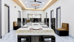A conference room with a long table, chairs, ceiling fans, and a view through the windows. - Premium Collection O Joka Industrial Plaza (Alipur)