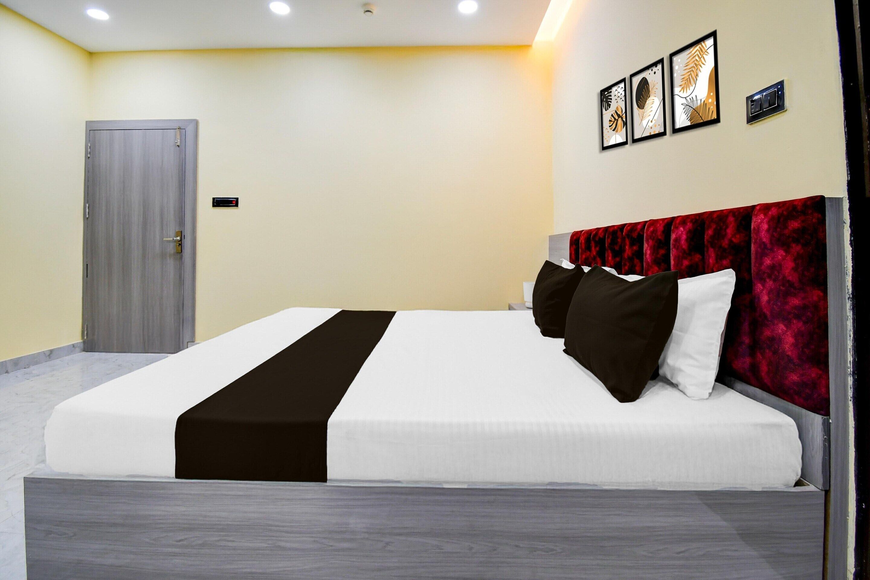 A modern hotel room with a bed, a door, and a wall-mounted control panel.