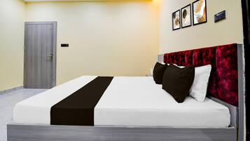 A modern hotel room with a bed, a door, and a wall-mounted control panel.
