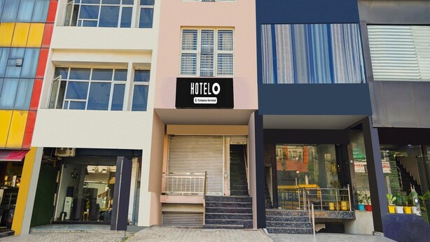 Un hotel de varios pisos con un llamativo letrero 'HOTEL', una escalera que conduce a la entrada y diferentes estilos de ventanas.