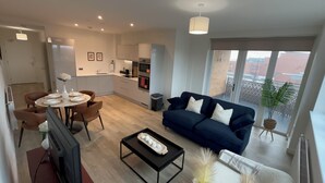 Un appartement moderne comprenant un coin repas, un salon avec canapé, une cuisine et de grandes fenêtres.