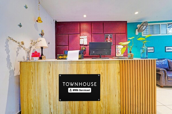 A reception desk with a sign reading 'TOWNHOUSE OYO-Serviced.' - Classic The Beige Hotel (Kozhenchery)