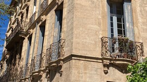 Um edifício histórico com varandas ornamentadas, grandes janelas circulares e uma placa com o nome.