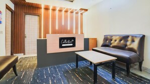 A reception area with a wooden slatted wall, a reception desk, a leather sofa, and a small table. - Saver Doubleroyal Inn (New Delhi)