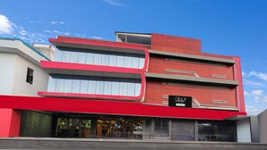 A modern building with a red and white facade, a visible storefront, and a clear sky. - Saver Doubleroyal Inn (New Delhi)