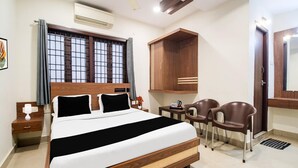 Ein Hotelzimmer mit Bett, Nachttisch, Sessel, Schreibtisch und Kleiderschrank.