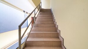 Eine Treppe mit Metallgeländer und beigen Stufen, die zu einer höheren Etage führt.