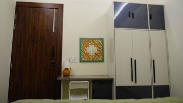A bedroom with a bed, a desk, a chair, a wardrobe, and a wall decoration.