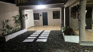 Un cortile con pavimento piastrellato, una porta nera e piante in vaso.