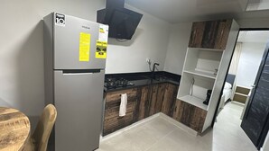 Una cucina compatta con frigorifero, fornello e mobili in legno.