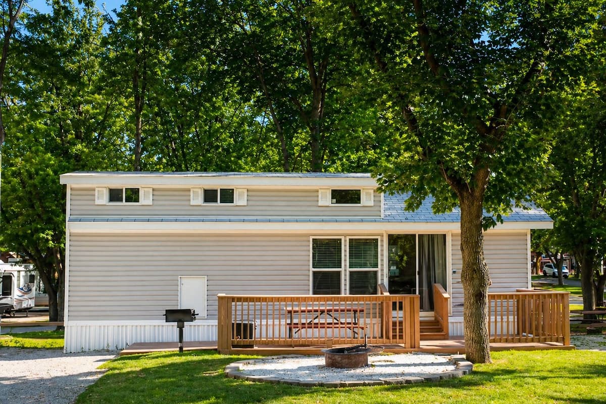 A mobile home with a front deck, a mailbox, and a fire pit.