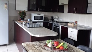 A kitchen with a microwave, stove, and granite countertop. - Rustic Red Serene & comfortable country home (Benoni North)
