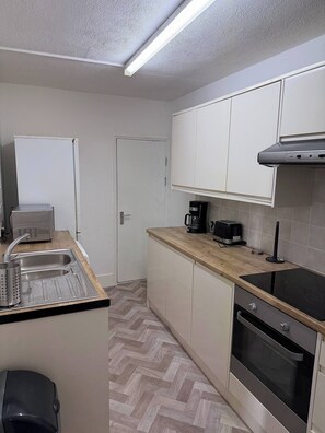 A compact kitchen with a sink, a toaster, a coffee maker, and an oven. - The Railway House, Colchester (Essex)