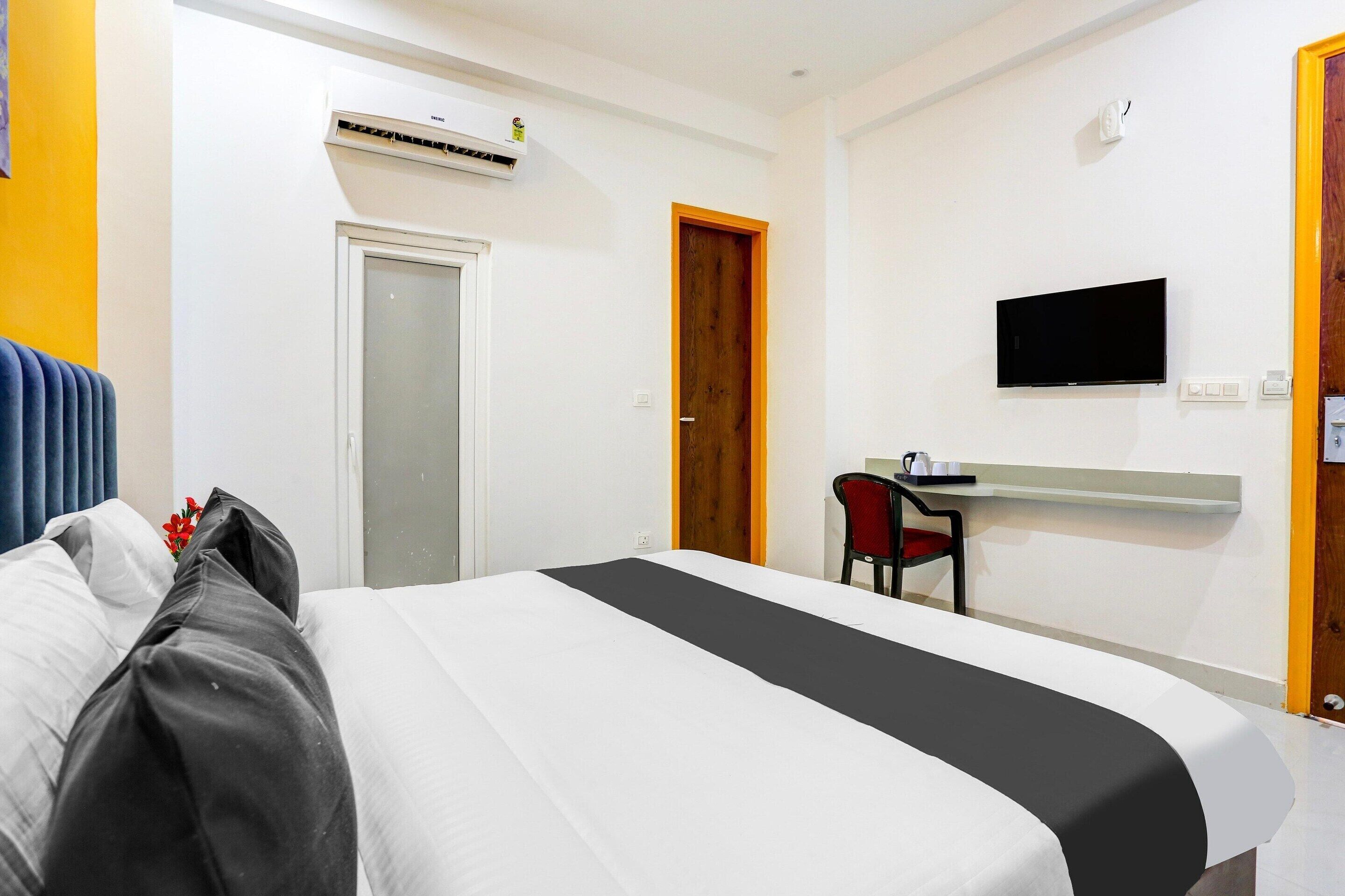 Ett hotellrum med en säng, ett skrivbord med en stol, en tv och en luftkonditioneringsanläggning.