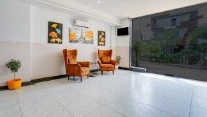 Eine Lobby mit zwei Sesseln, einem Blumentopf und Kunstwerken an der Wand.